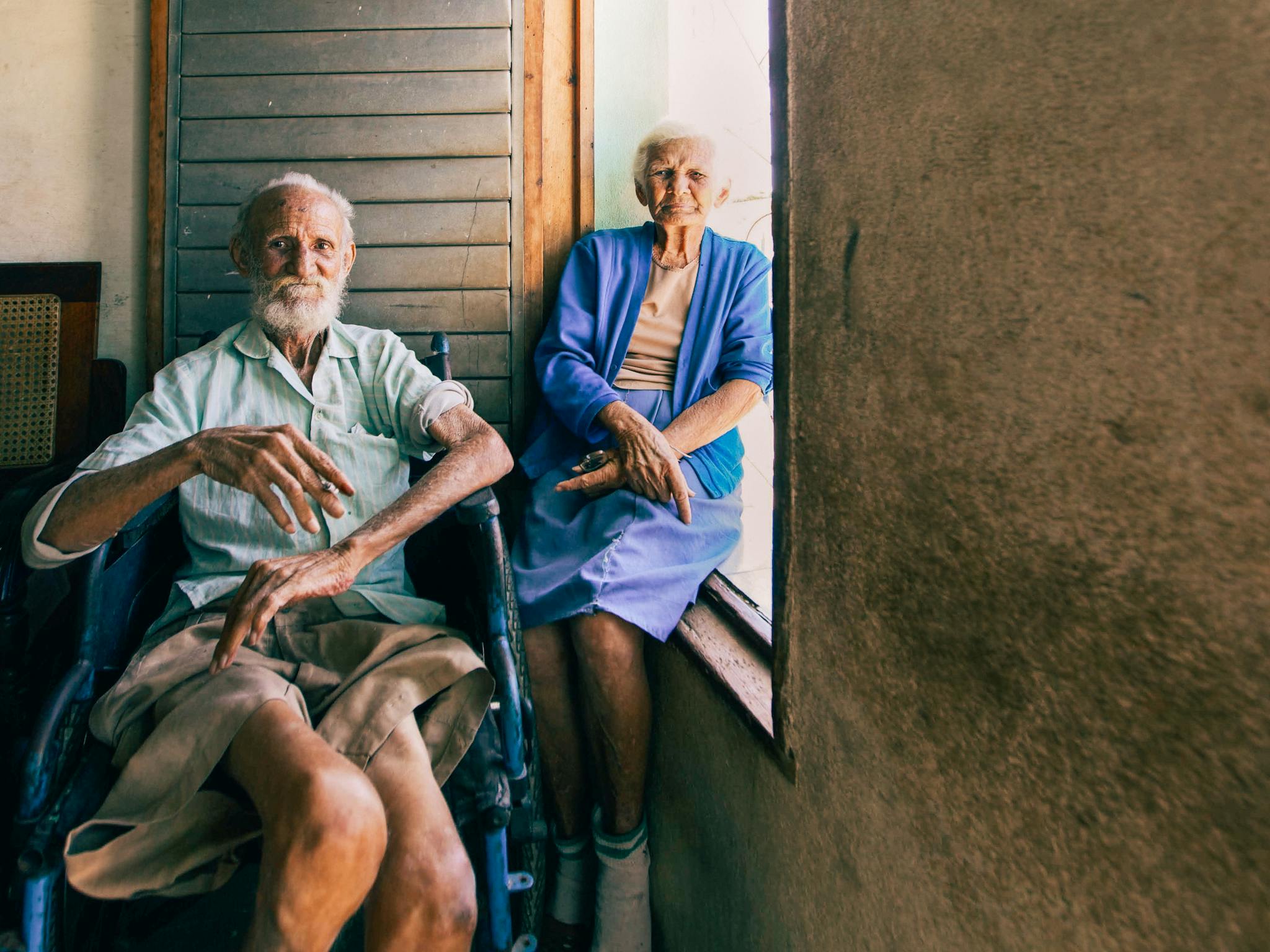 An elderly couple sitting by a window, capturing a serene moment indoors with natural light.